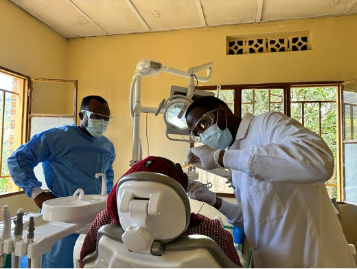 A Rwandan dentist instructing a medical student while treating a dental patient