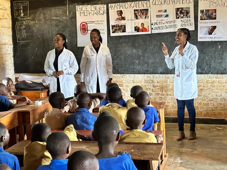 three Rwandan medical students teach a class to third graders
