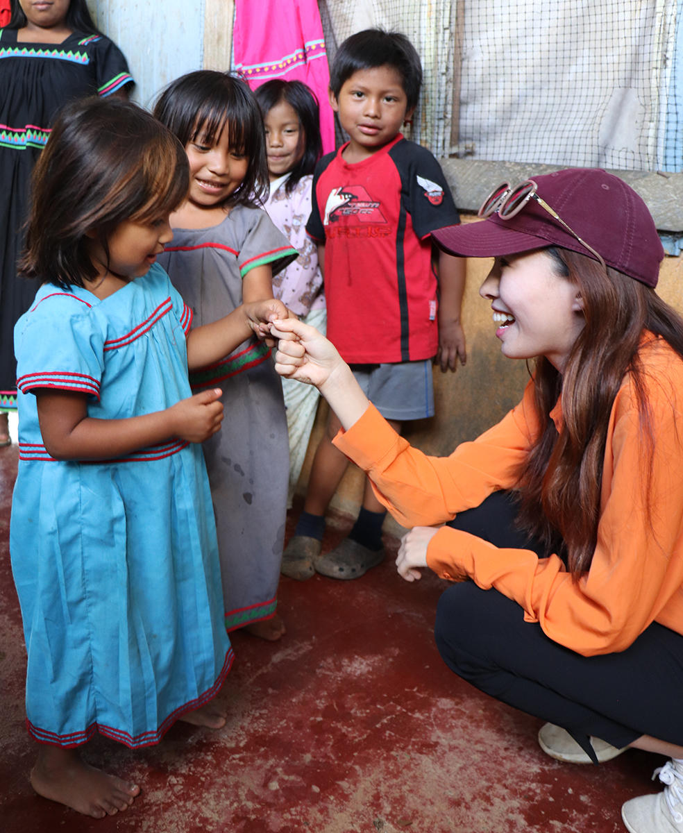 woman with baseball cap interacting with children