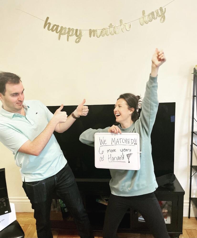 Two people celebrating, holding sign that reads "We matched: 6 more years at Harvard!"