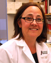 Dr. Francesca Gori wearing a lab coat and smiling at a lab bench